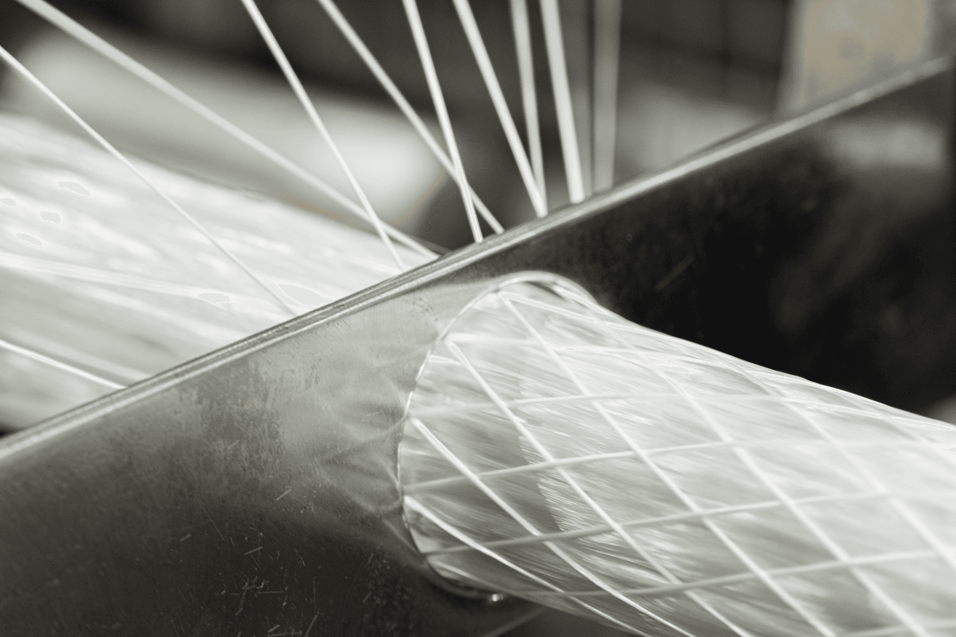 White glass-fibre strands braiding around a metal die in a pultrusion machine