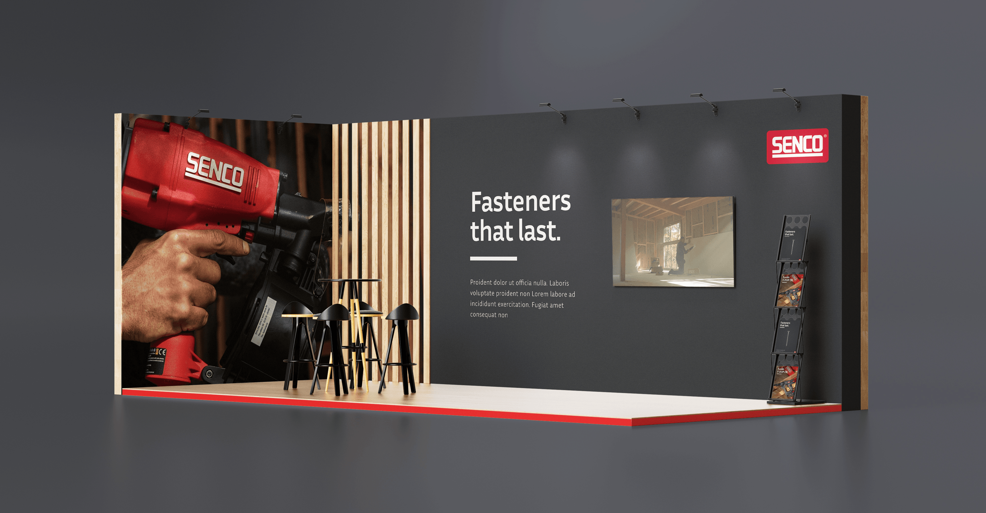 A trade-show stand concept for Senco: a large photograph of a hand driving a red Senco tool on one wall, "Fasteners that last" on a dark grey wall opposite, and a seating area between them