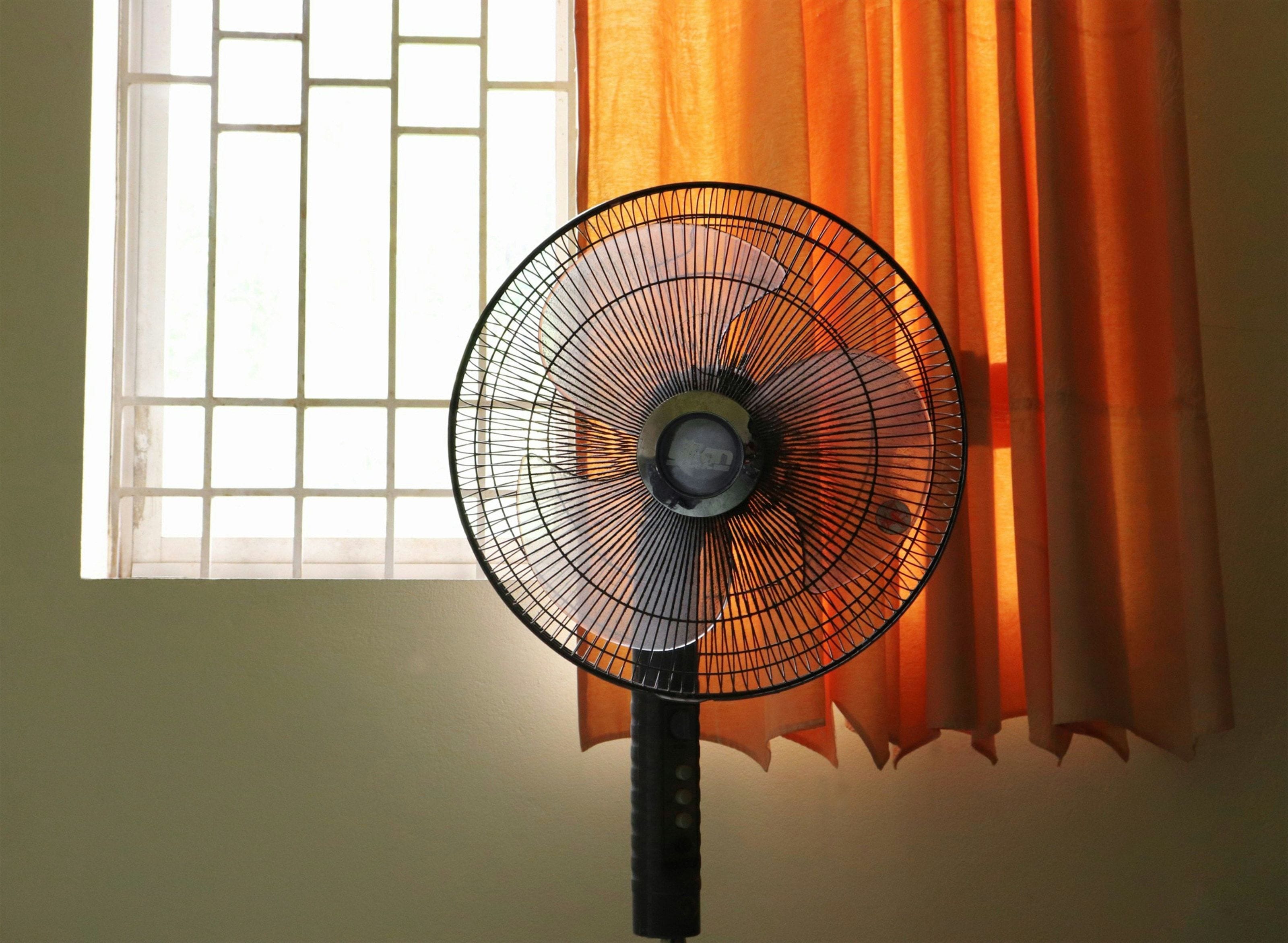 Standing fan by an orange curtain