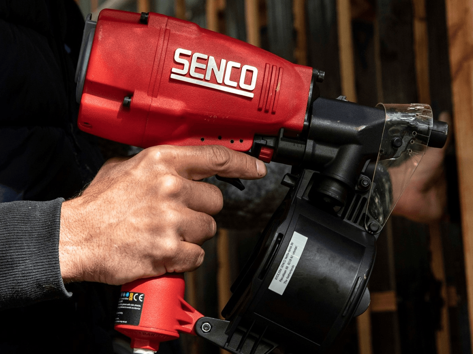 A photograph of someone driving a red Senco tool into timber, with Fasteners, Tools and Service in the navigation