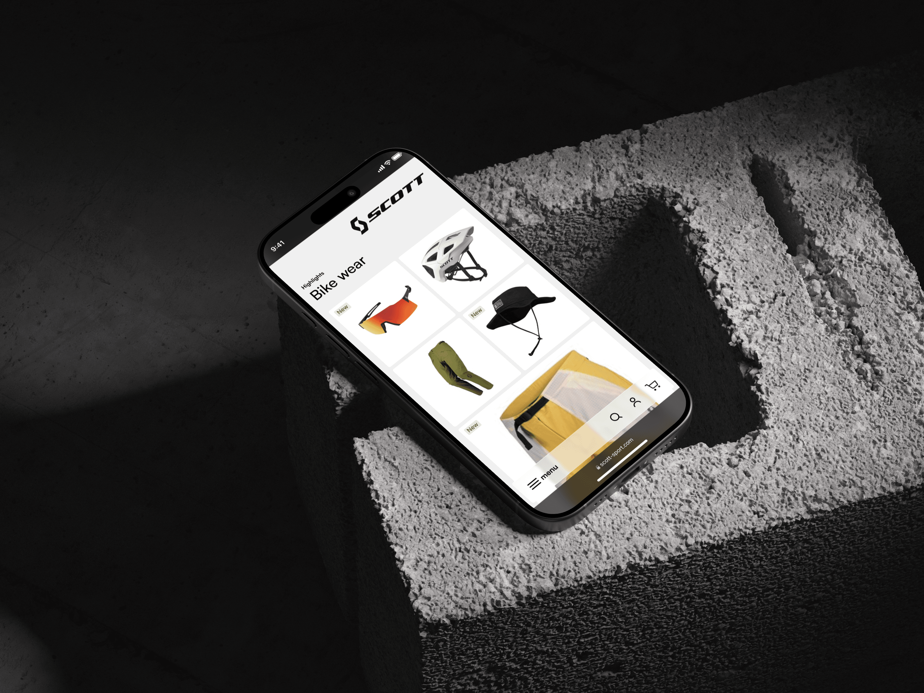 A phone on concrete showing a bike wear grid - helmet, sunglasses, cap, gloves and shorts laid out on white