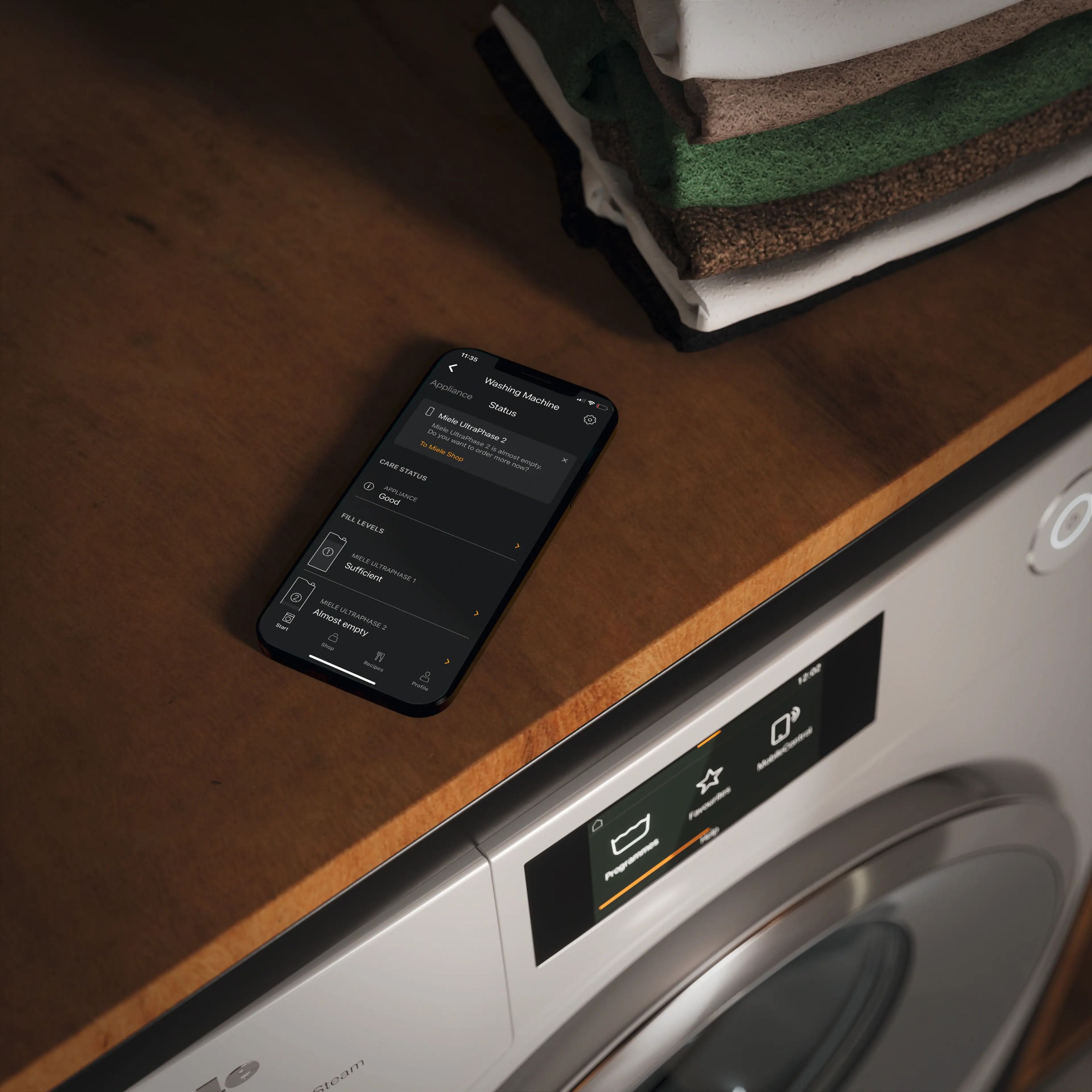 A phone laying on top of the counter of the miele washing machine, miel app is opened