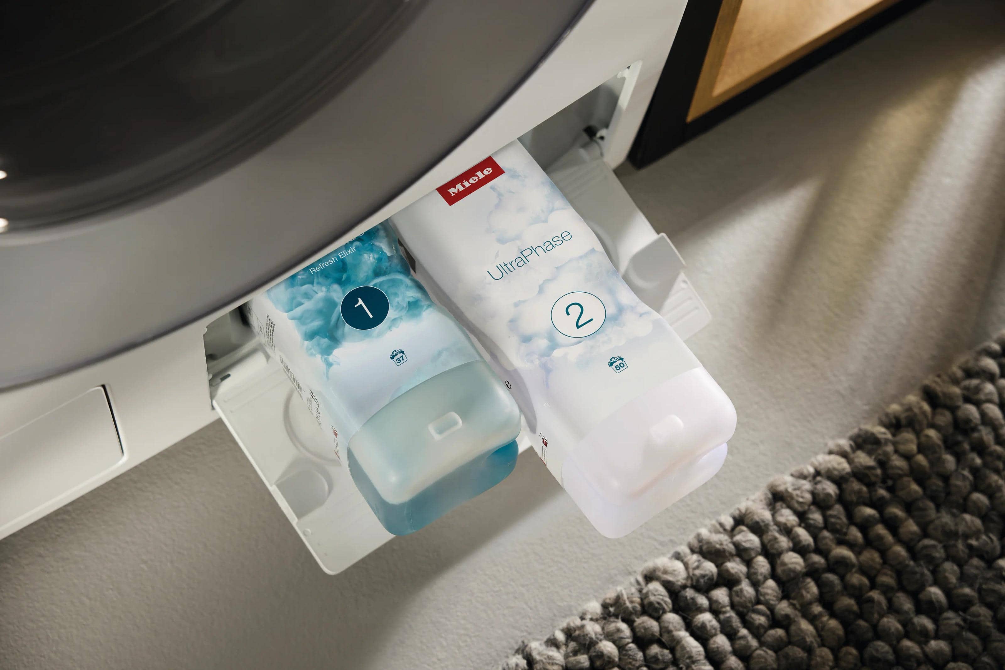 Two Miele UltraPhase cartridges, numbered 1 and 2, loaded into a washing machine’s detergent drawer