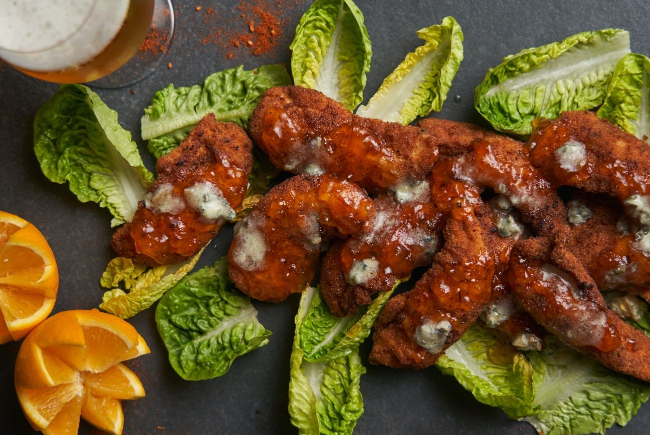 Chicken nuggets with chutney and blue cheese, served on a plate with salad and a beer
