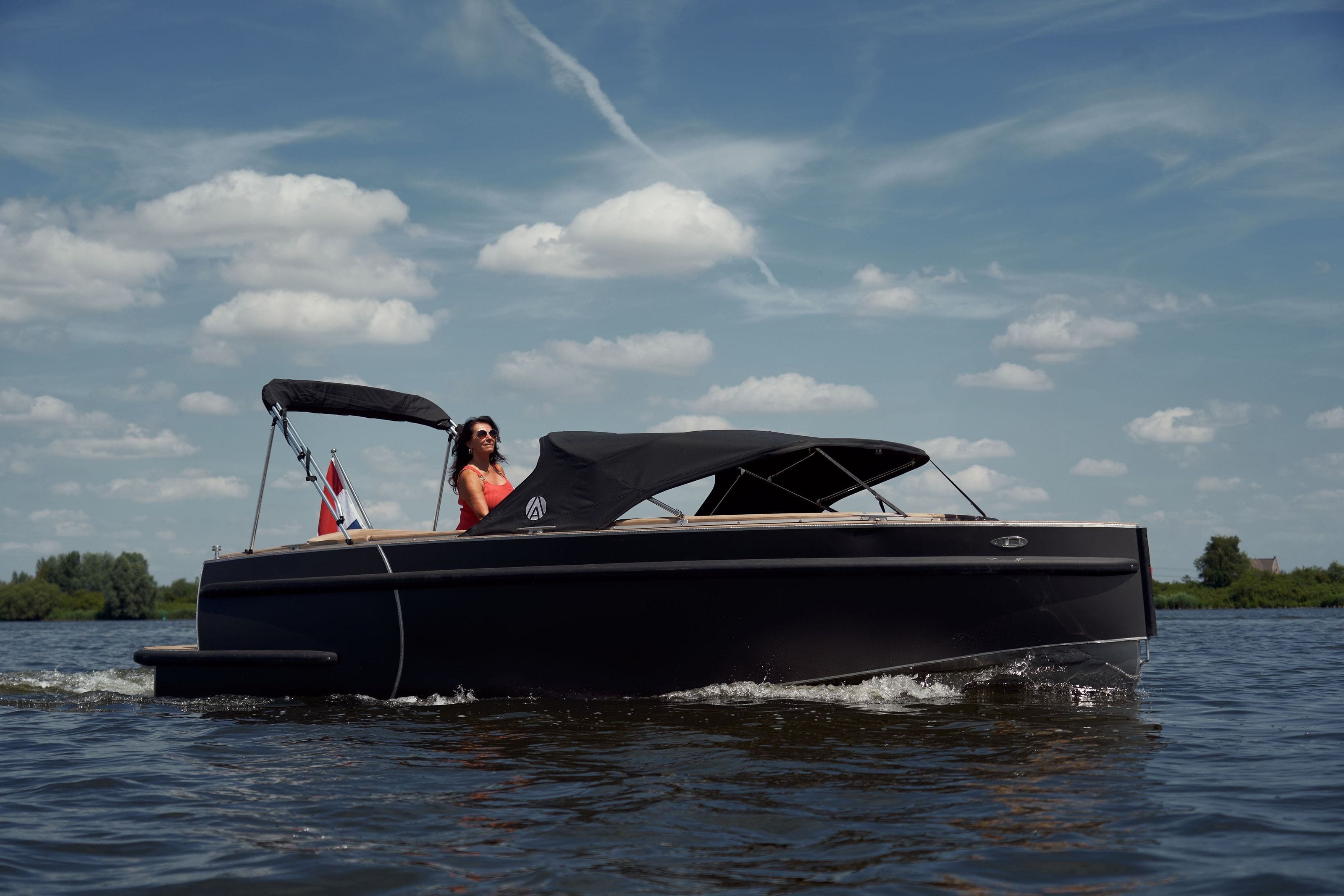 The same electric boat seen from the side, 1 person aboard, out on the open water of the Veluwemeer under a wide sky