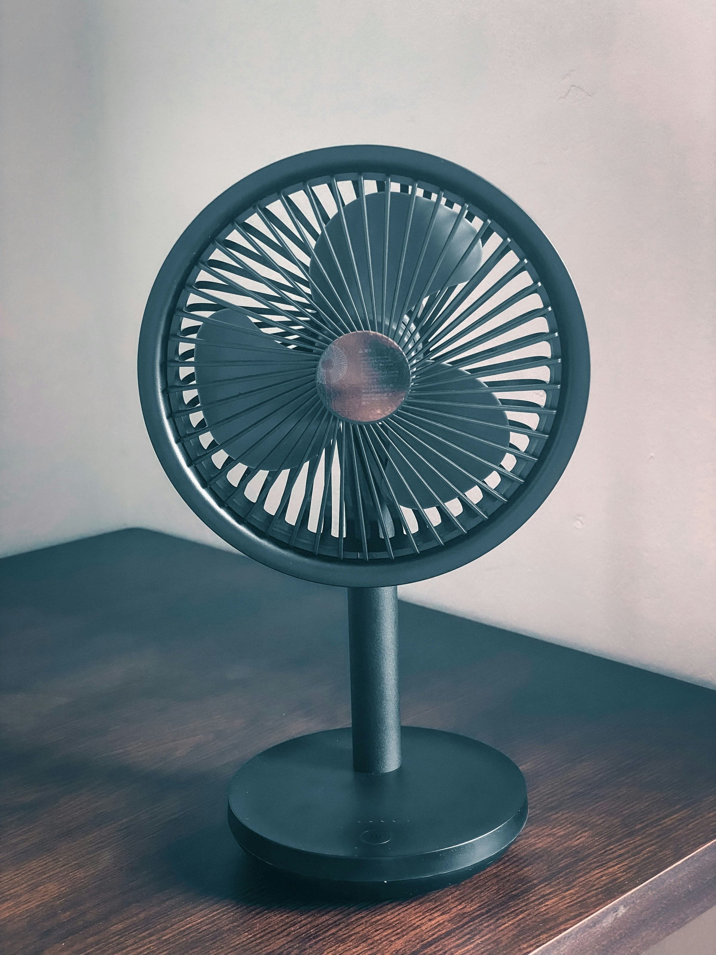 Dark green desk fan on a wooden table