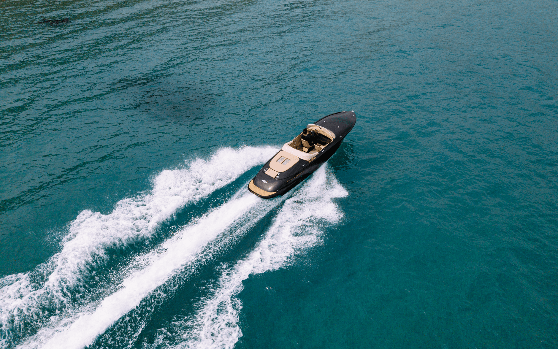 A Hermes Speedster seen from above, cutting a long white wake across turquoise water