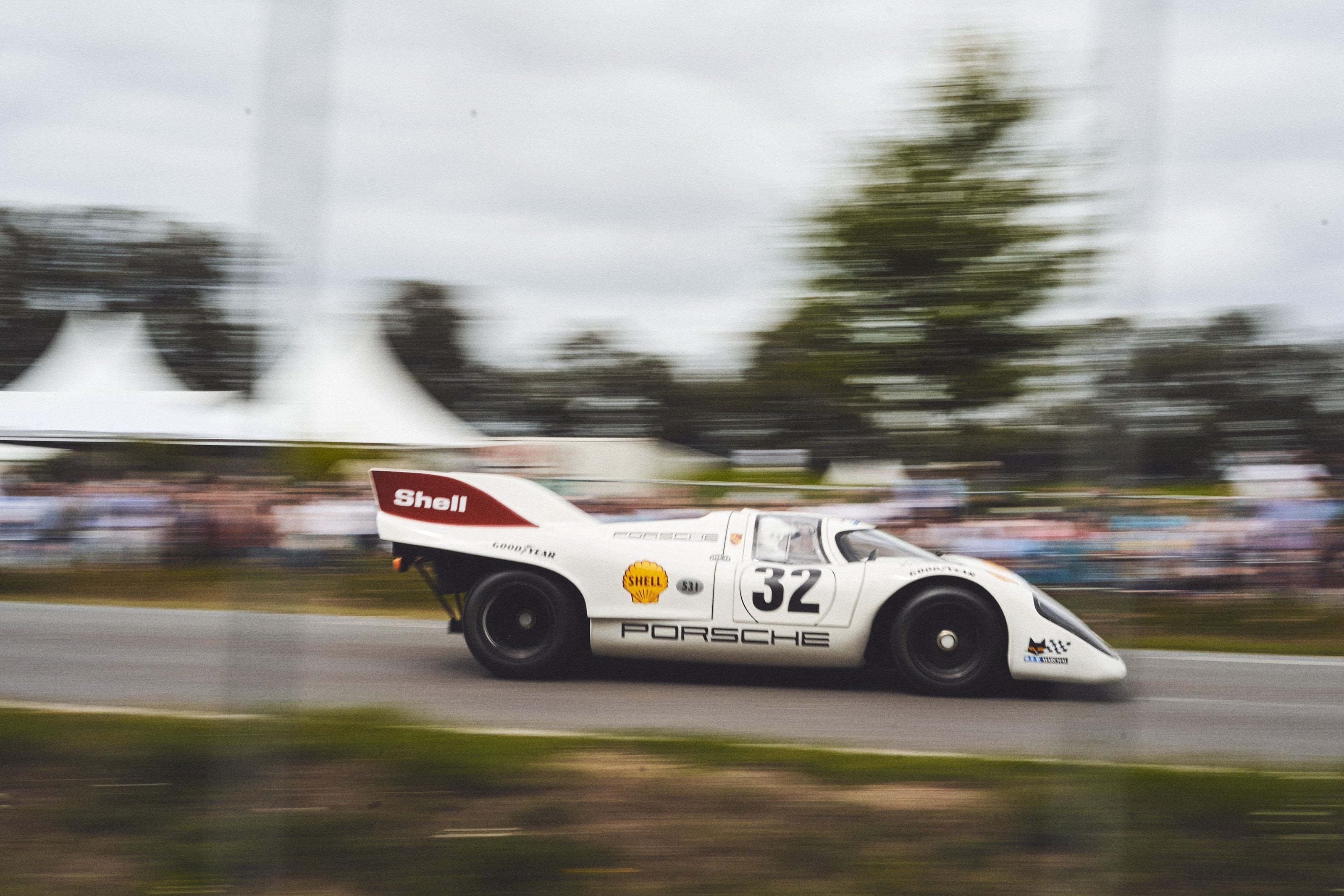 A white Porsche 917 endurance racer, number 32 in Shell livery, caught mid-corner with the background blurred by the panning motion